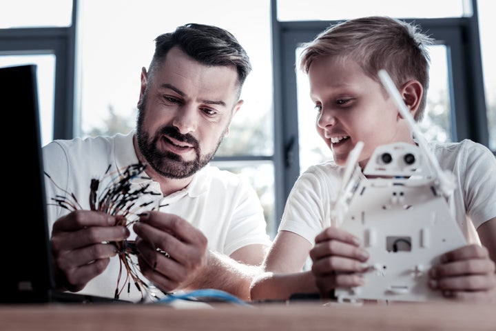 Un padre y un hijo construyen juntos un robot. 