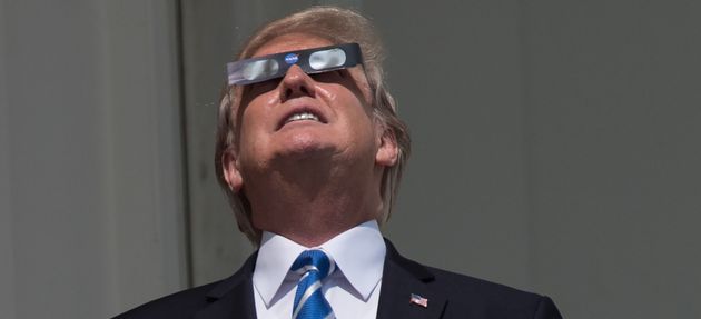 President Donald Trump looks up at the partial solar eclipse from the balcony of the White House on August 21, 2017.