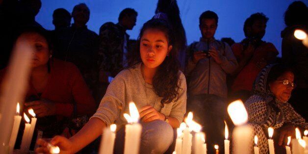 Nepalese people pay tributes to the victims of the April 25 earthquake, as they light candles near the destroyed landmark Dharahara tower in Kathmandu, Nepal, Thursday, May 7, 2015. The quake killed thousands and injured many more as it flattened mountain villages and destroyed buildings and archaeological sites in Kathmandu. (AP Photo/Niranjan Shrestha)