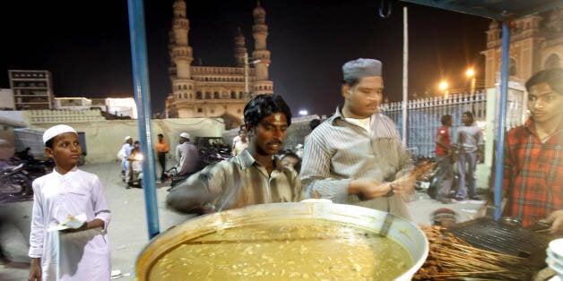 HYDERABAD, INDIA: An Indian vendor prepares kebabs and non-vegetarian delicacies in his stall outside the Mecca mosque with the Char Minar in the background in Hyderabad, 20 October 2005. Indians, like many millions of Muslims around the world, are observing the holy month of Ramadan -- a month of fasting and spiritual purity during which they refrain from eating, drinking or sex from dawn until dusk. AFP PHOTO/Prakash SINGH (Photo credit should read PRAKASH SINGH/AFP/Getty Images)