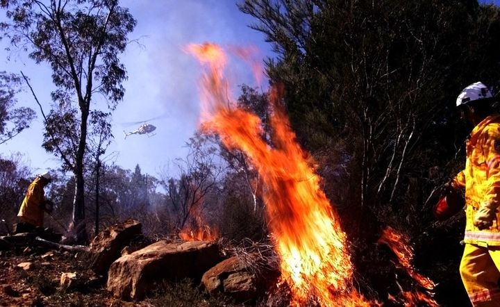 Firefighters drop incendiary devices from a helicopter during a hazard reduction burn off Weddin Mountain National Park.