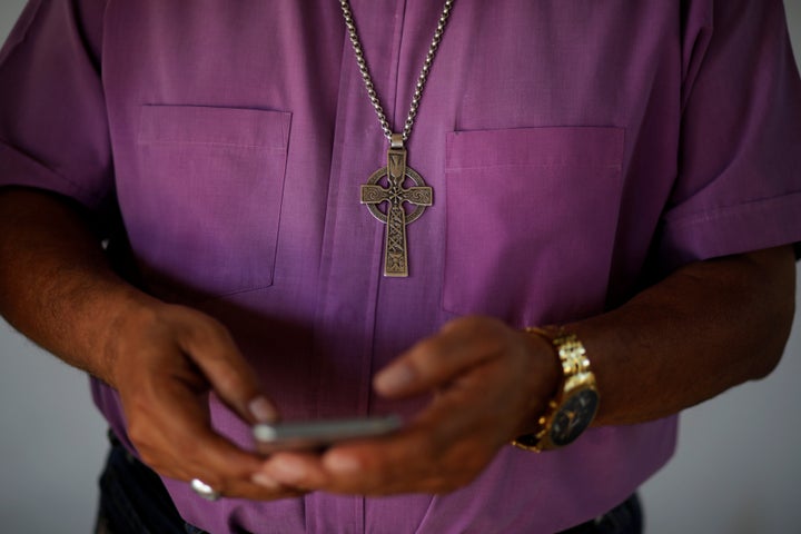 Bishop David Alvarado, of the Anglican Episcolpal Church in El Salvador, checks messages on his cellphone after an interview