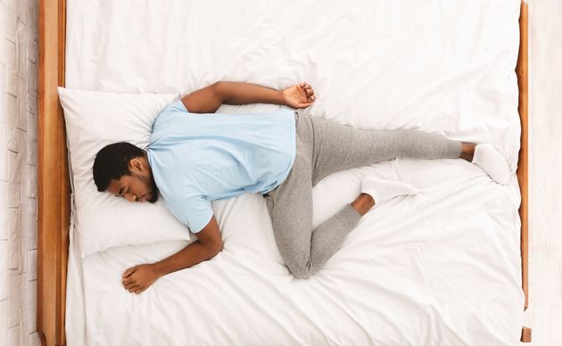 Comfortable pose for sleep. Black millennial guy sleeping, lying on stomach in bed, top view