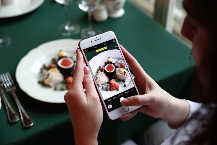 MOSCOW, RUSSIA - DECEMBER 12, 2019: A woman uses a smartphone to take a picture of Olivier salad (Russian salad) in the Pushkin Cafe at Tverskoi Boulevard. Image used for representational purposes only.