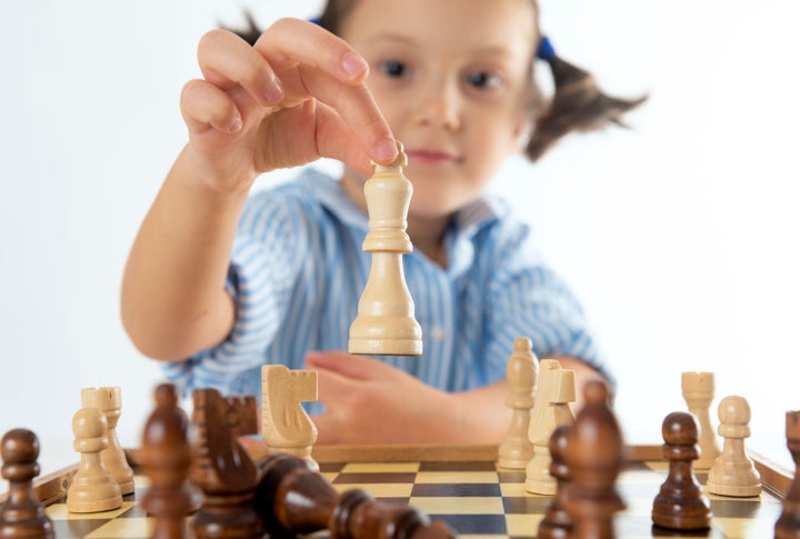 Una niña pequeña jugando al ajedrez. 
