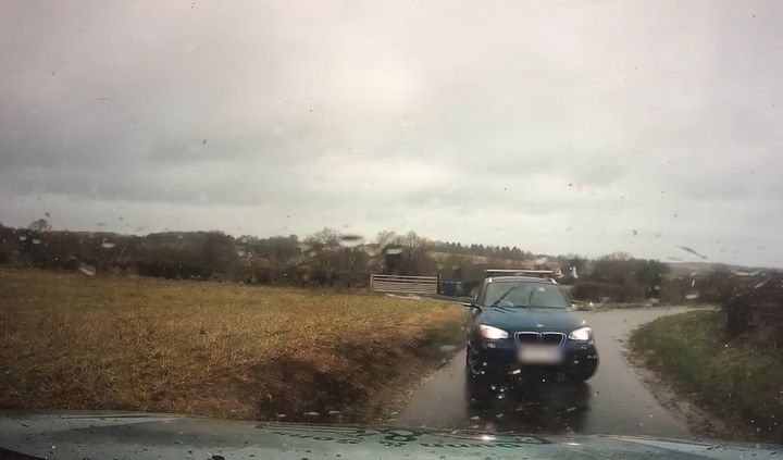 Undated handout still from dashcam footage of a blue BMW on the wrong side of the road near RAF Croughton. 