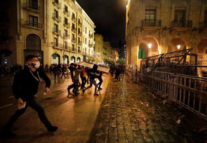 Anti-government protesters throw stones against the riot police, during ongoing protests against the political elites who hav