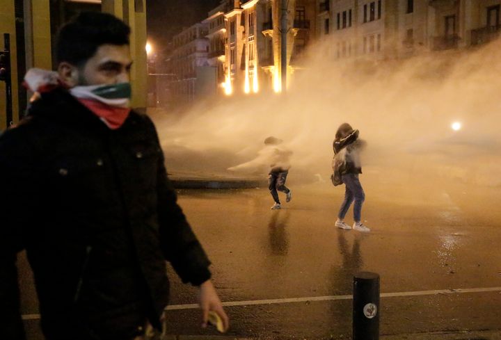 Anti-government protesters are sprayed by a water canon, during ongoing protests against the political elites who have ruled the country for decades, in Beirut, Lebanon, Sunday, Jan. 19, 2020. (AP Photo/Hassan Ammar)