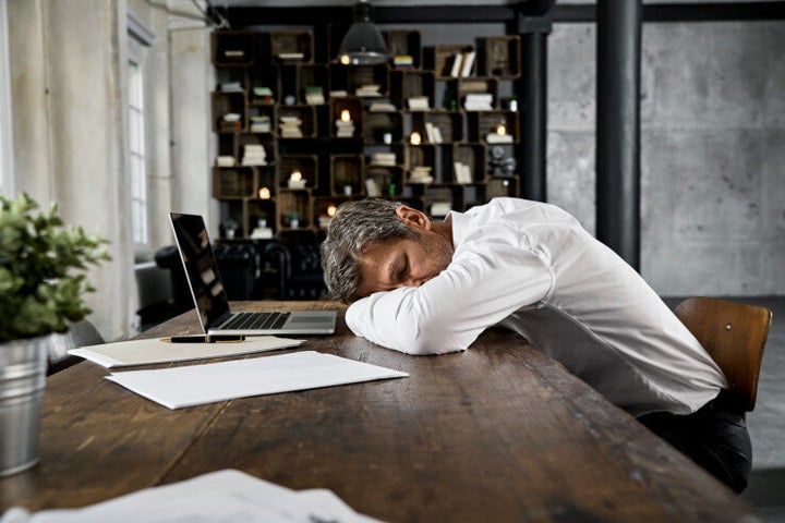 Portrait of mature business man sleeping on desk in loft