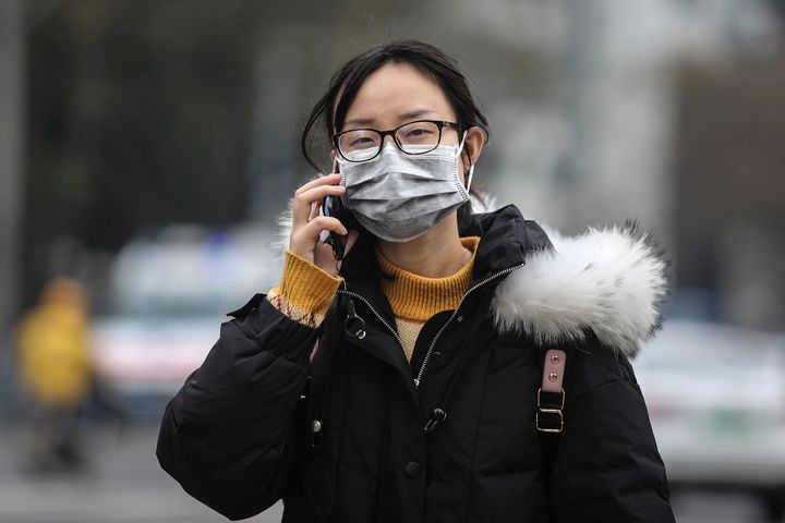A woman wearing a mask walks past the seafood market that has been linked to cases of a new coronavirus that is believed to have originated in Wuhan, China.