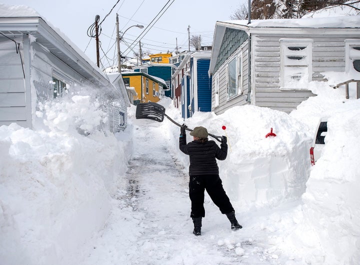A woman clears snow off a roadway in St. John's on Sunday, days after a major winter storm wreaked havoc on parts of Newfoundland with massive amounts of snowfall.