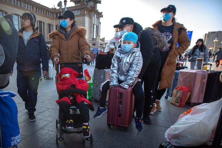 Travelers wear face masks outside of the Beijing Railway Station on Jan. 20, 2020. China reported a sharp rise in the number of people infected with a new coronavirus on Monday, including the first cases in the capital. The outbreak coincides with the country's busiest travel period as millions board trains and planes for the Lunar New Year holidays. 
