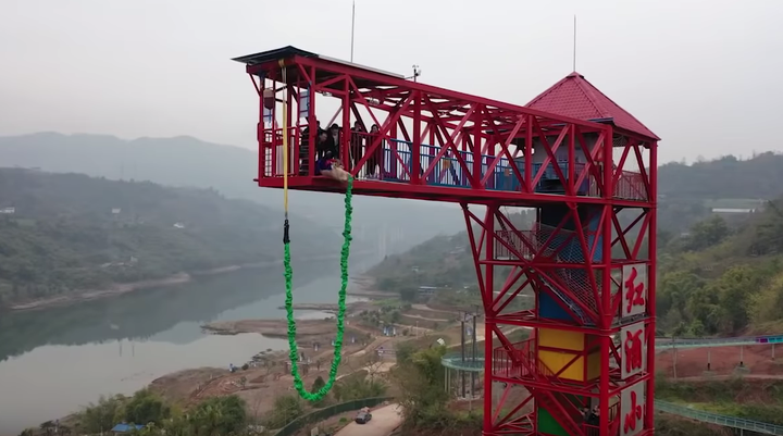 A still of the pig being taken to the edge of the bungee jumping tower.