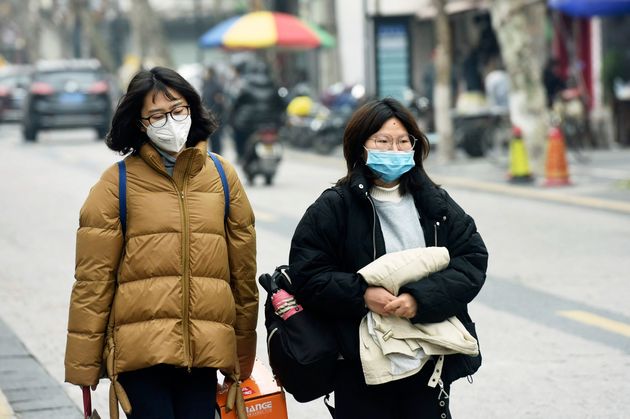 火曜日、中国東部のZ江省の杭州の通りを歩いているときに、女性はフェイスマスクを着用しています...
