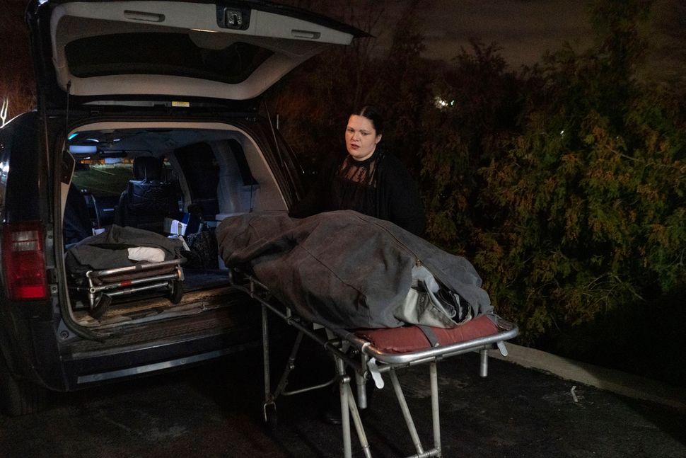 Castro puts a body into the back of her company's van to transport it to a funeral home in Manhasset, New York. She usually has 12-hour workdays, but is on call 24/7.