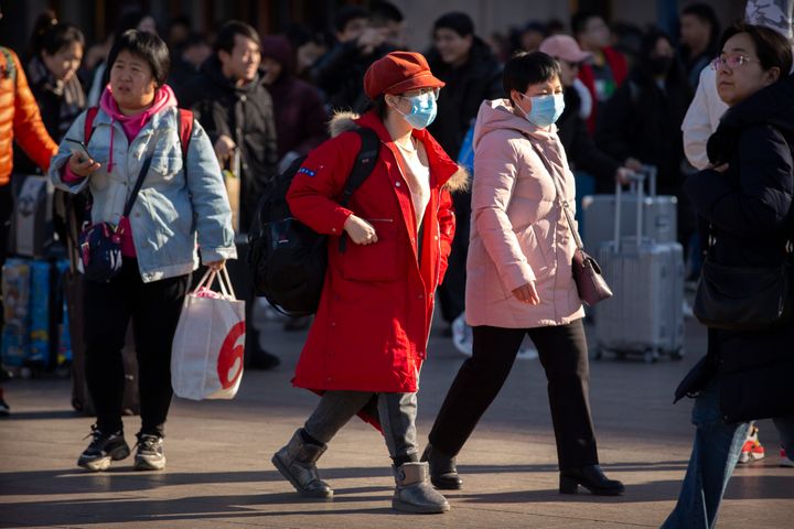 Travelers wear face masks as they walk outside of the Beijing Railway Station in Beijing, Monday, Jan. 20, 2020. 