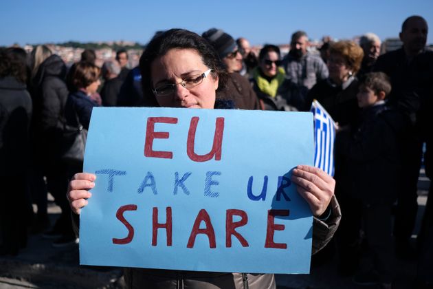 Κάτοικος της Λέσβου κρατάει χαρτόνι με το σύνθημα «Ε.Ε. πάρε το μερίδιο σου» γραμμένο στο αγγλικά.