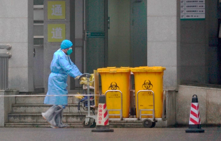 Staff move bio-waste containers past the entrance of the Wuhan Medical Treatment Center, where some infected with a new virus are being treated.