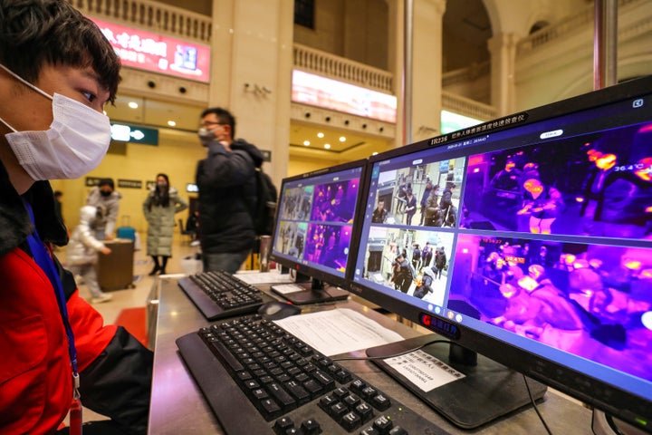 A staff member wearing a mask monitors thermal scanners that detect temperatures of passengers at the security check inside the Hankou Railway Station in Wuhan on Tuesday.