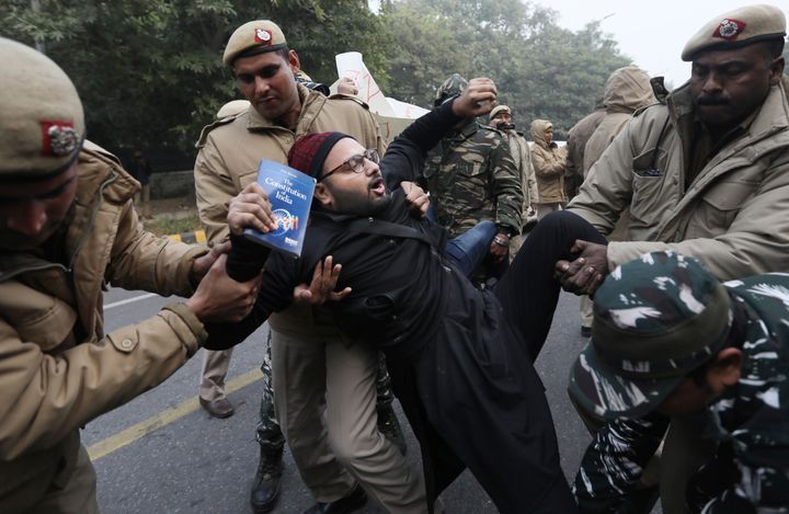 Police officers detain a protesting against the new citizenship law outside Uttar Pradesh Bhawan on Friday, Dec. 27, 2019. 