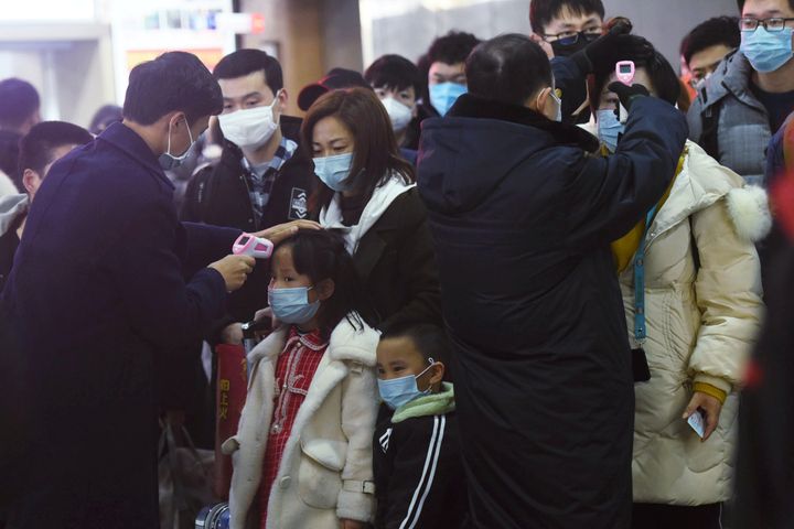 Staff members check body temperatures of the passengers arriving from the train from Wuhan to Hangzhou, at Hangzhou Railway Station prior to the lockdown coming into effect. 
