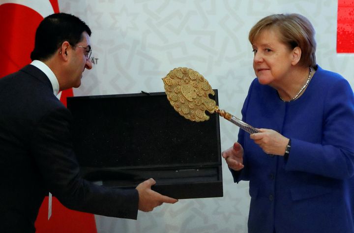 Η Καγκελάριος της Γερμανίας Αγκελα Μέρκελ αντιδρά ξαφνιάζοντας με τον ενθουσιασμό της καθώς δέχεται εθιμοτυπικά δώρα από τον Τούρκο Πρόεδρο Ταγίπ Ερντογάν στην Κωνσταντινούπολη, στις 24 Ιανουαρίου 2020. REUTERS/Umit Bektas