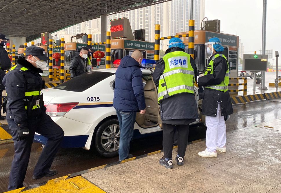 Police officers wearing masks check a car for smuggled wild animals at an expressway toll station following the outbreak 
