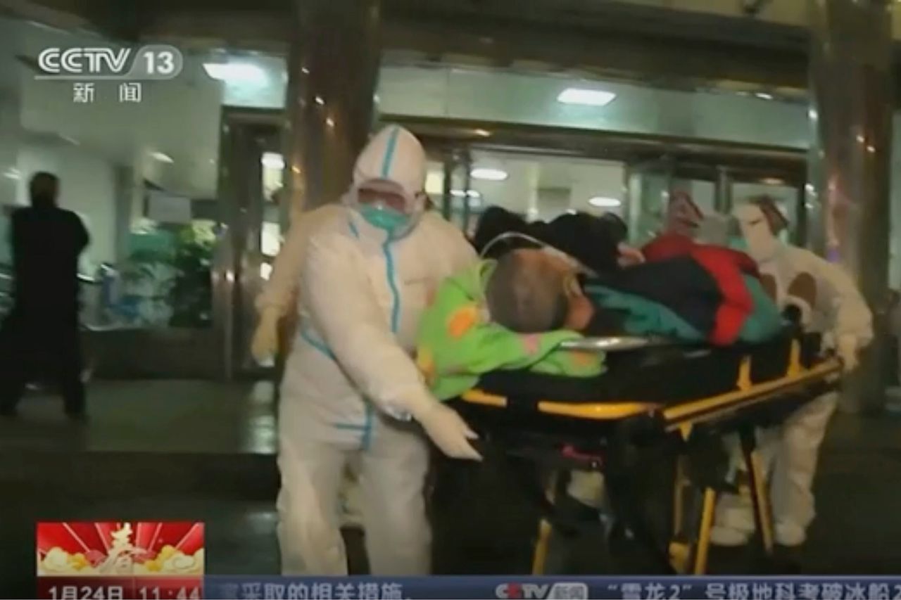 Φωτογραφία από κάμερα ασφαλείας κλειστού κυκλώματος δείχνει έναν ασθενή πάνω σε φορείο να μεταφέρεται στο ασθενοφόρο, από νοσηλευτές που φορούν προστατευτικές στολές.