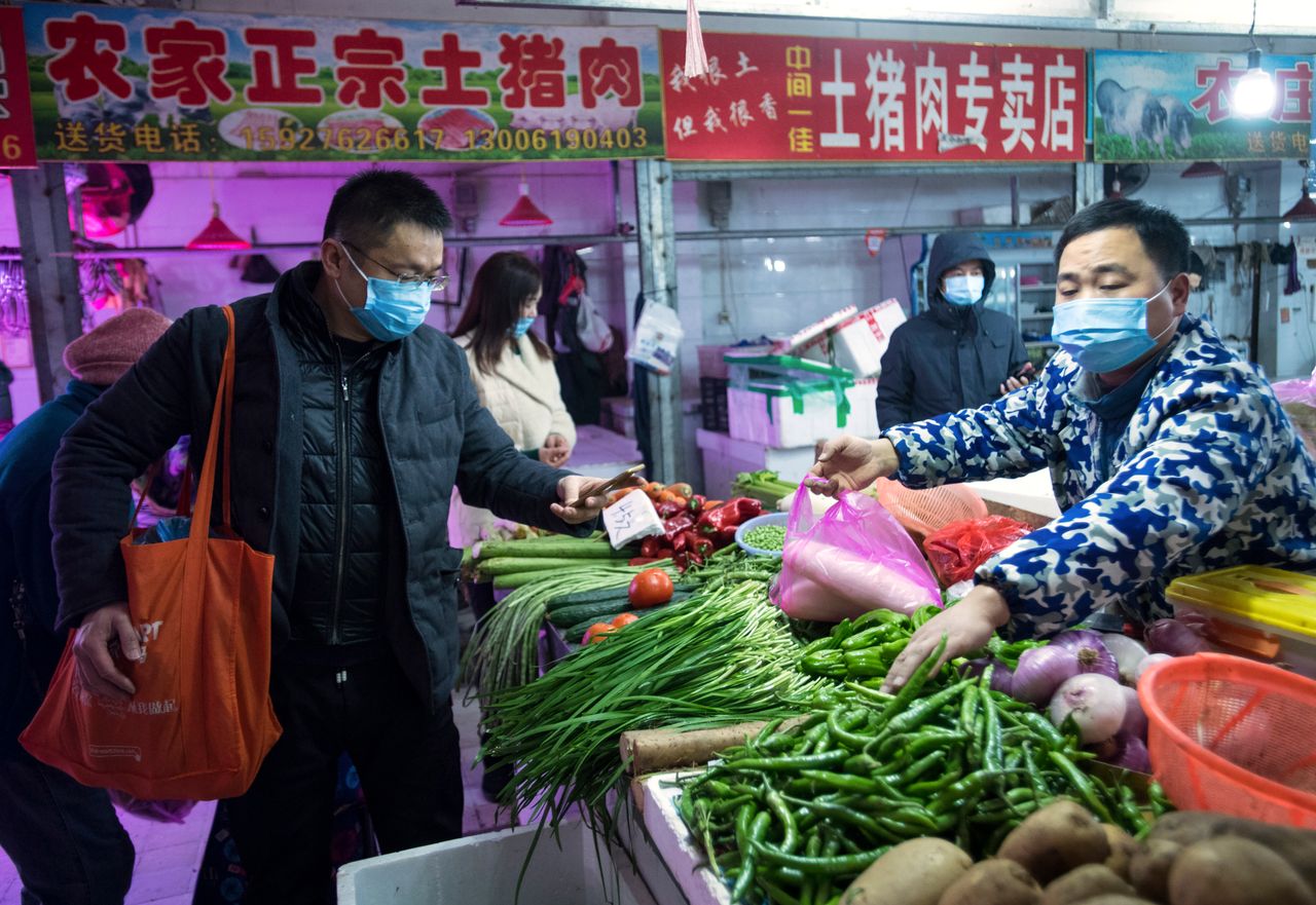 People shop for vegetables at a market in Wuhan