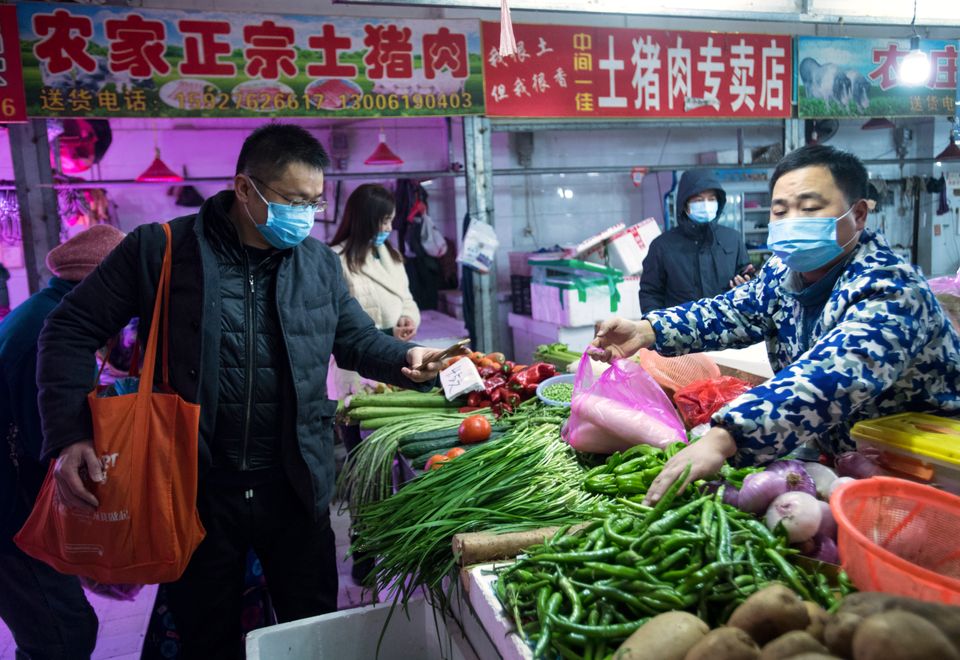 People shop for vegetables at a market in Wuhan