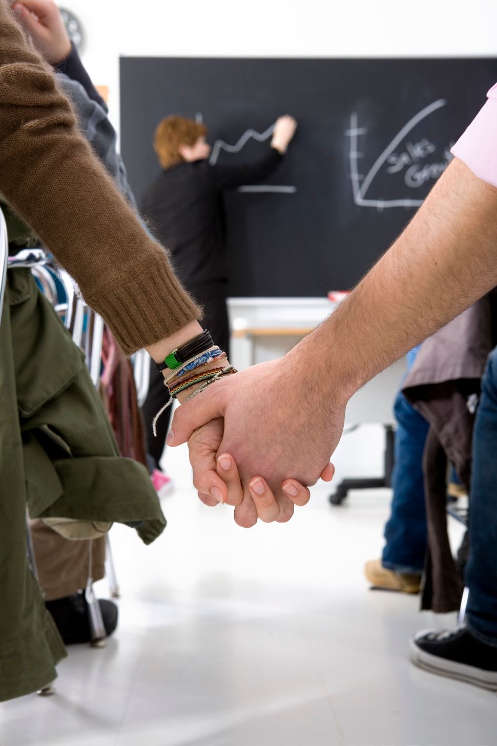 Two students hold hands in class.