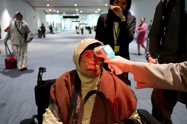 A health official scans the body temperature of a passenger as she arrives at the Soekarno-Hatta International Airport in Tangerang, Indonesia, on Wednesday.