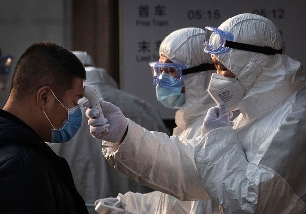 A Chinese health worker checks the temperature of a woman entering a subway station.