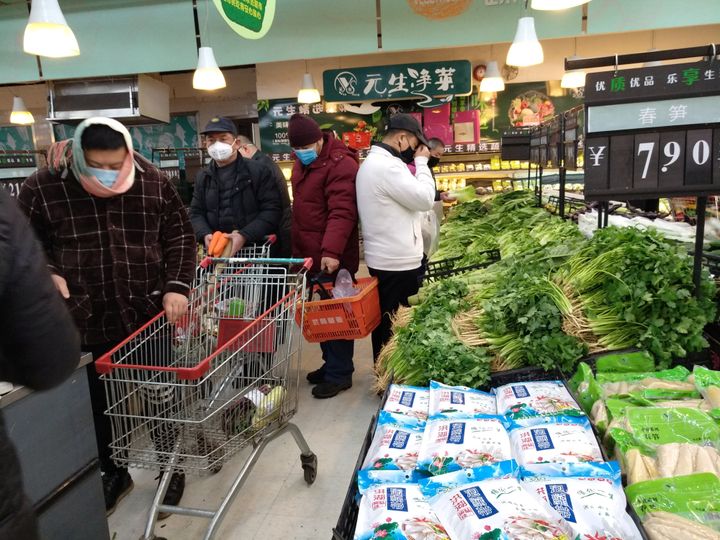 People wearing masks shop at a supermarket on the second day of the Chinese Lunar New Year.