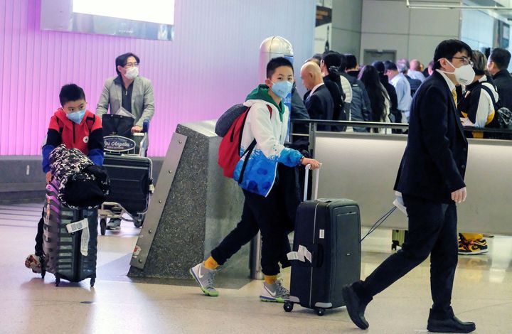 Passengers wearing face masks arrive at the Los Angeles International Airport from Shanghai, China, on Sunday after a positive case of the coronavirus was announced in the Orange County suburb of Los Angeles.