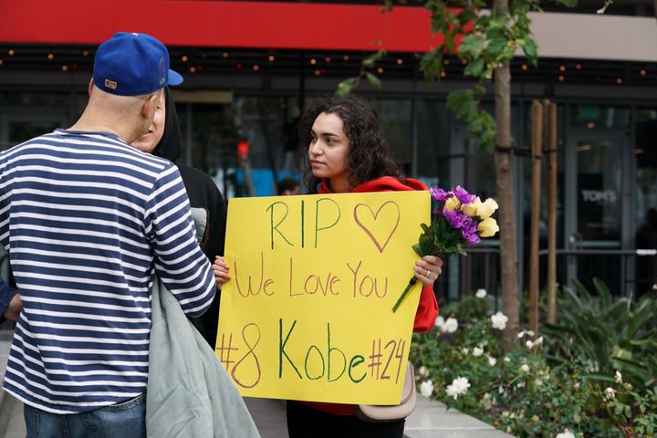 ステイプルズセンターの前で「私たちはあなたを愛している。どうか安らかに」と書かれたメッセージを掲げる