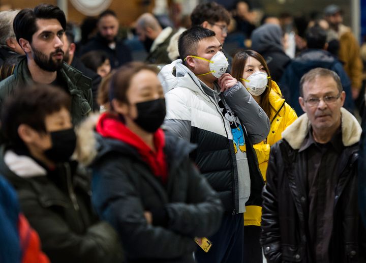 People wear masks following the outbreak of a new virus as people arrive from the International terminal at Toronto Pearson International Airport in Toronto on, Jan. 25, 2020.