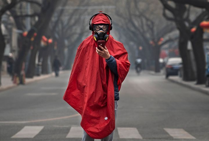 A Chinese man wears a protective mask, goggles and coat as he stands in a nearly empty street during the Chinese New Year holiday on January 26, 2020 in Beijing. 