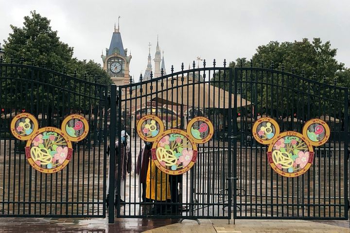 Employees stand at the gates of the Shanghai Disney Resort, which announced that it will be closed indefinitely from Saturday, in Shanghai, on Jan. 25, 2020. 