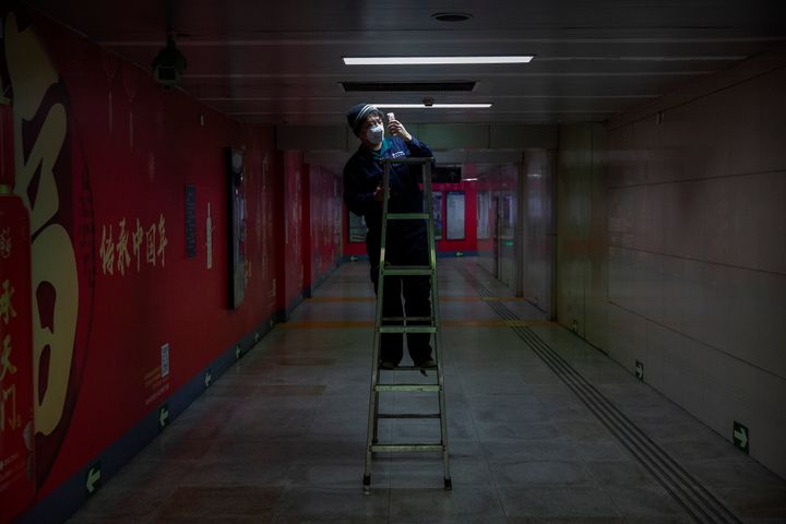 ...αλλά και κάτω από το έδαφος, στον υπόγειο σταθμό του μετρό στο Πεκίνο, οι «κανόνες» είναι ίδιοι. Αντικαθιστώντας τον λαμπτήρα - αλλά με μάσκα ο αρμόδιος τεχνικός. (AP Photo/Mark Schiefelbein)