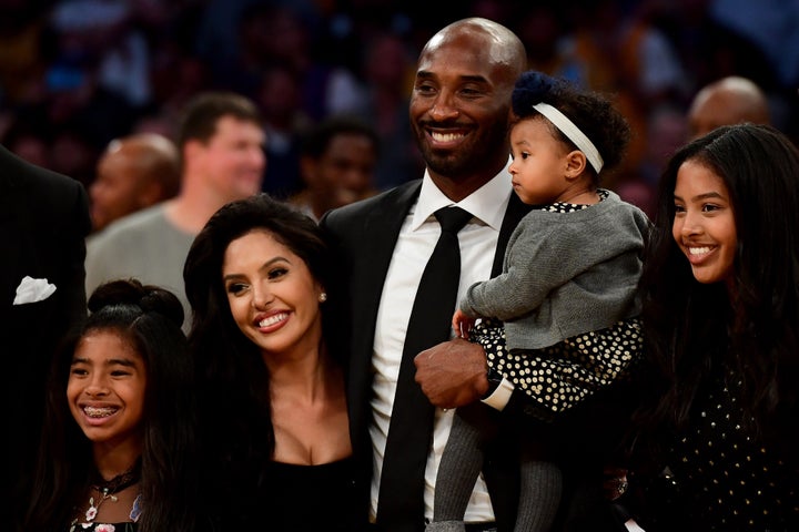 Kobe Bryant poses with his family at halftime after both his No. 8 and No. 24 Los Angeles Lakers jerseys are retired at Stapl