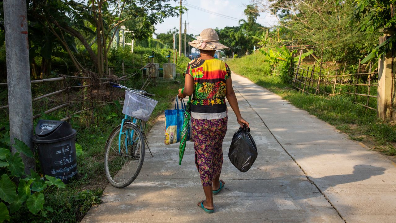 A woman carries a recycled bag and plastic bag.