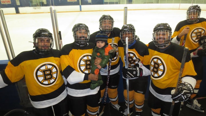 Bobby Sahni holds his second son, six-year-old Rayaan, with Sahni's teammates.