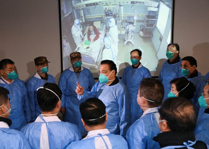 Chinese Premier Li Keqiang, wearing a mask and protective suit, speaks to medical workers on Jan. 27 as he visits the Jinyintan hospital where the patients of the new coronavirus are being treated following the outbreak, in Wuhan, China.