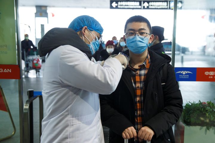 中国の空港で、医療当局者から体温を計られている男性＝2020年1月27日