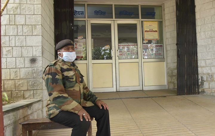 A guard is seen wearing a face mask as he sits outside the SMS hospital on January 27, 2020 in Jaipur.