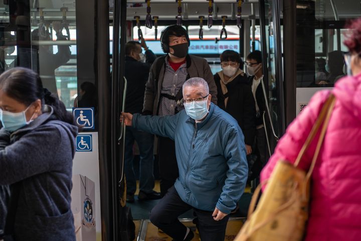 Passengers wearing face masks get off a bus in Macau, China