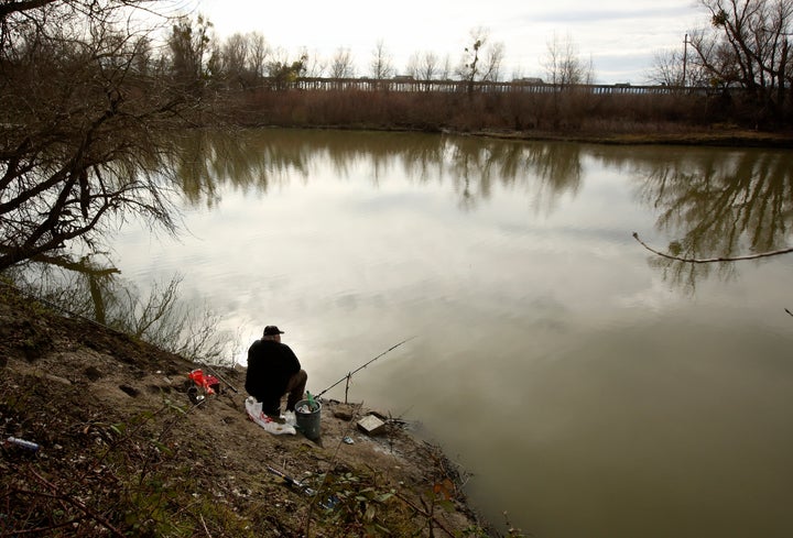 A fisherman sits along the slough where the body of an infant, Nikko Lee Perez, was discovered in Yolo County in 2007, near W