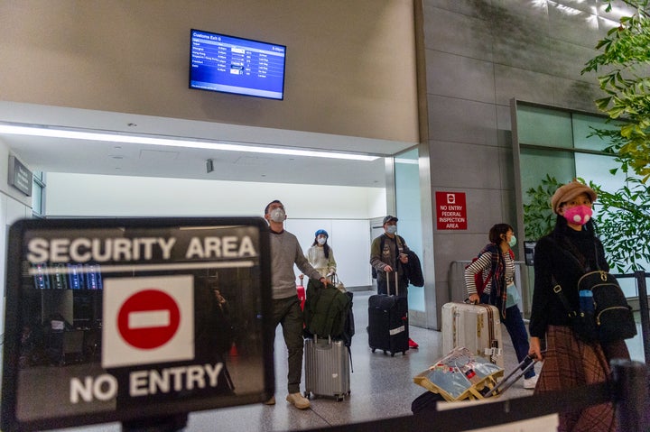 Passengers wearing face masks walk out of the international terminal at the San Francisco International Airport in Millbrae, California.