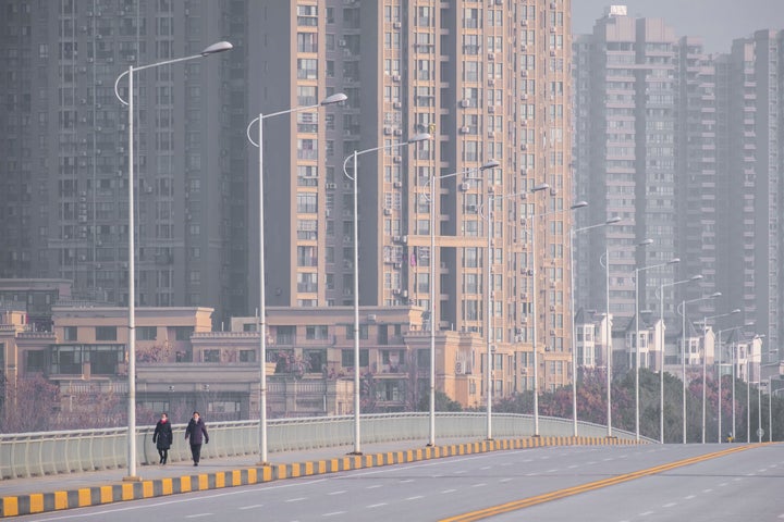 People wearing face masks walk down a deserted street in Wuhan in central China's Hubei Province, on Jan. 28, 2020.&nbsp;